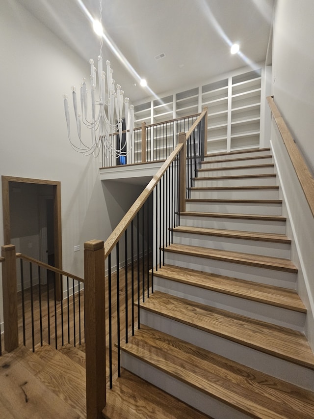 stairs with hardwood / wood-style flooring and a chandelier