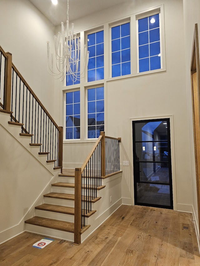 entryway with a towering ceiling, hardwood / wood-style floors, and a notable chandelier