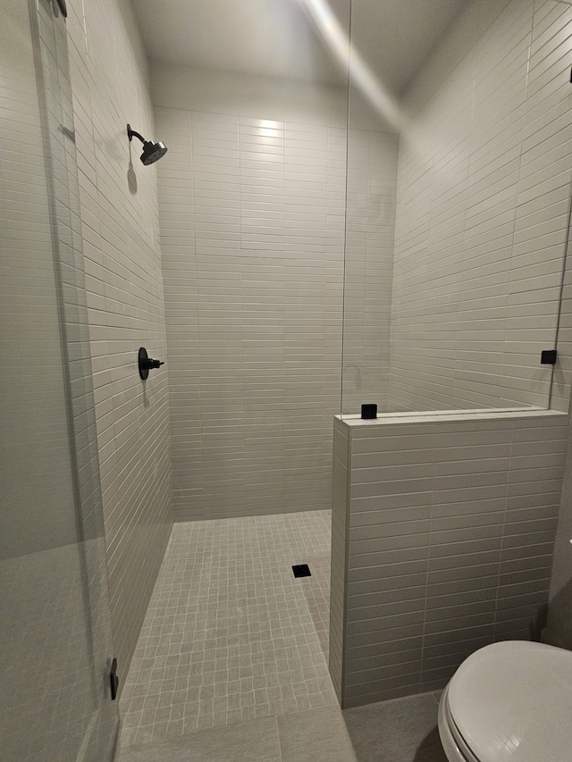 bathroom featuring toilet and a tile shower