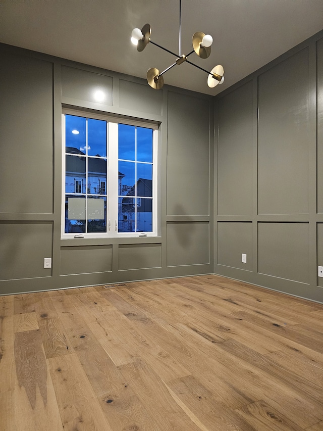 empty room with a notable chandelier and light wood-type flooring