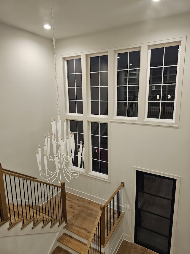 staircase with a chandelier and wood-type flooring