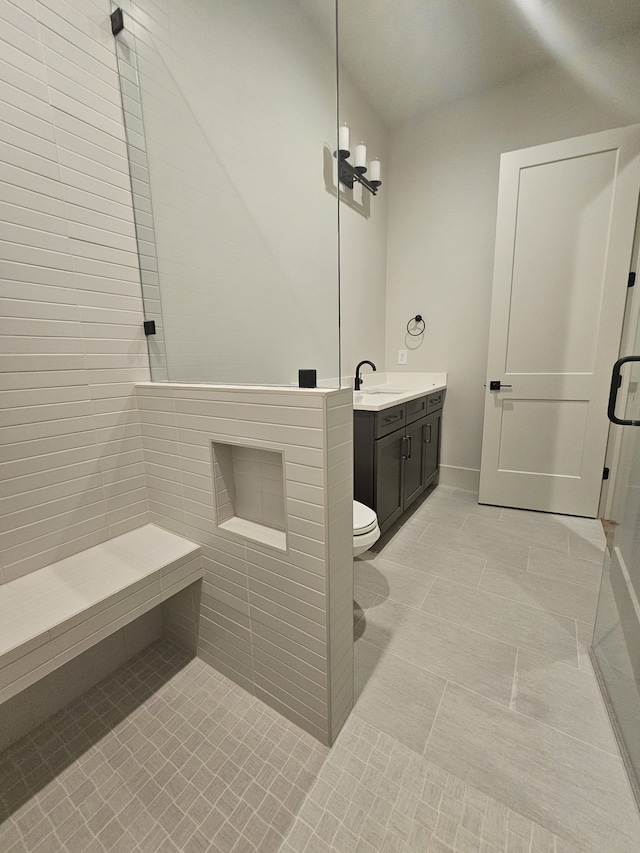 bathroom with tile patterned floors, tiled shower, toilet, and vanity