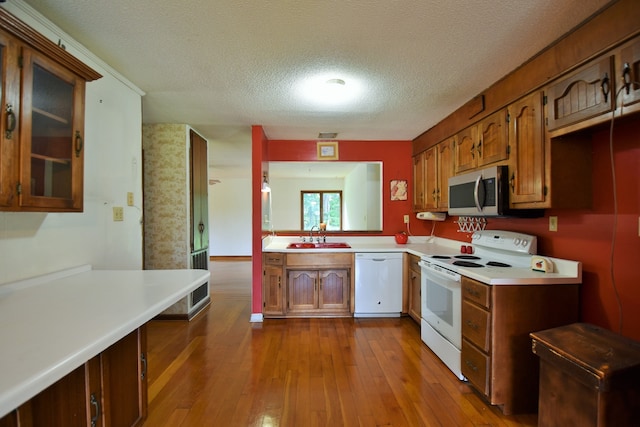 kitchen featuring white appliances, sink, a textured ceiling, and light hardwood / wood-style flooring