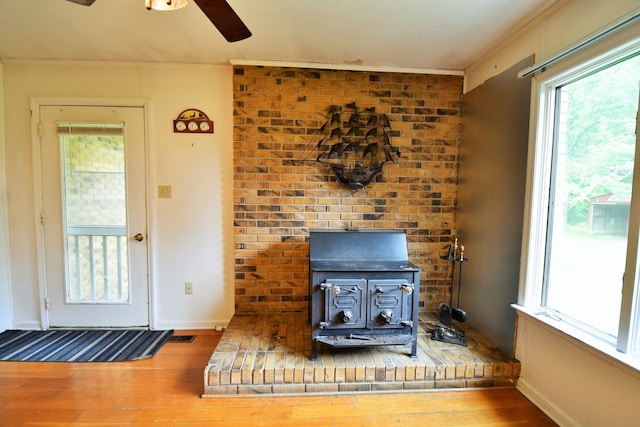 details with ceiling fan, hardwood / wood-style flooring, and a wood stove