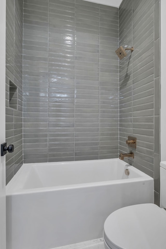 bathroom with toilet and tiled shower / bath