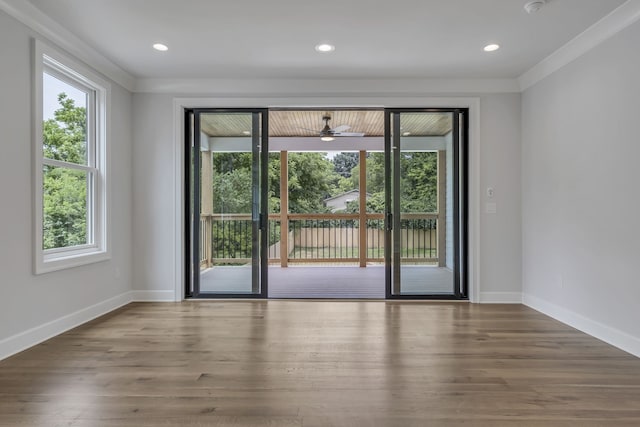 spare room with ornamental molding, a healthy amount of sunlight, and wood-type flooring