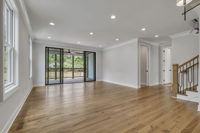 empty room with ornamental molding, light wood-type flooring, and a healthy amount of sunlight