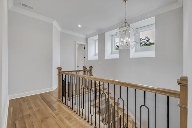 hallway with light wood-type flooring, a chandelier, and ornamental molding