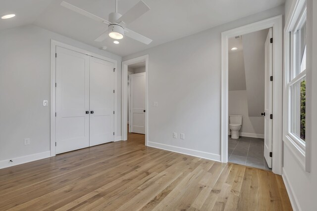 unfurnished bedroom with vaulted ceiling, light hardwood / wood-style flooring, a closet, connected bathroom, and ceiling fan