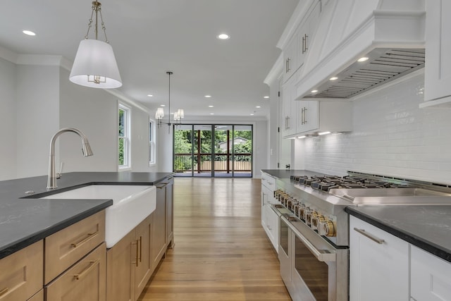 kitchen featuring decorative light fixtures, premium range hood, double oven range, light brown cabinets, and white cabinetry