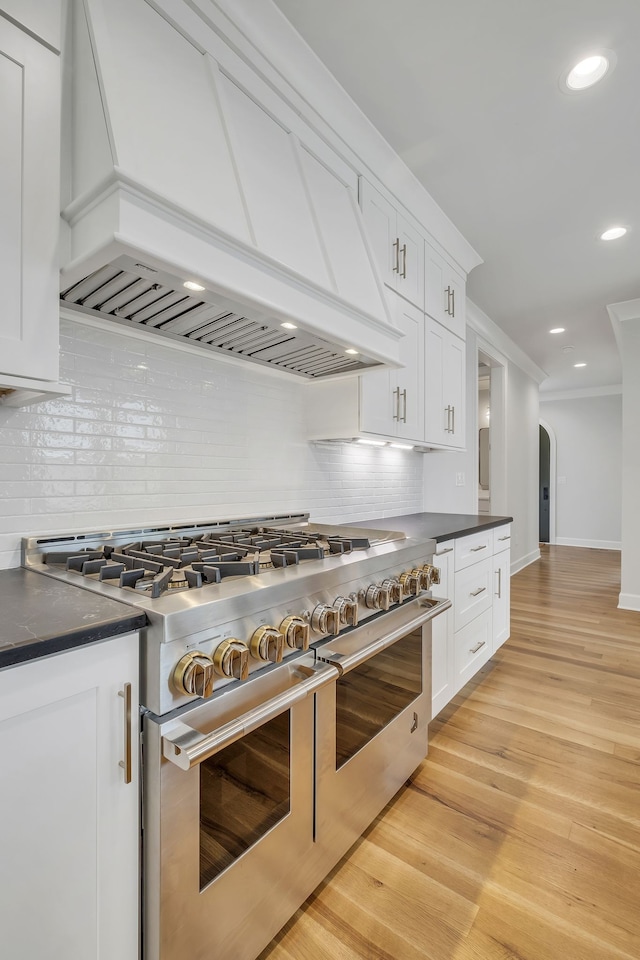 kitchen with white cabinetry, custom exhaust hood, decorative backsplash, and double oven range