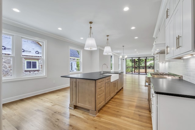 kitchen featuring white cabinetry, a spacious island, sink, and hanging light fixtures