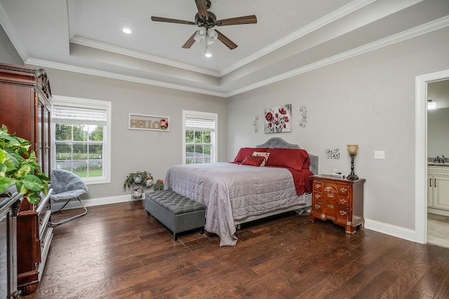 bedroom with a raised ceiling, crown molding, ceiling fan, dark wood-type flooring, and ensuite bathroom