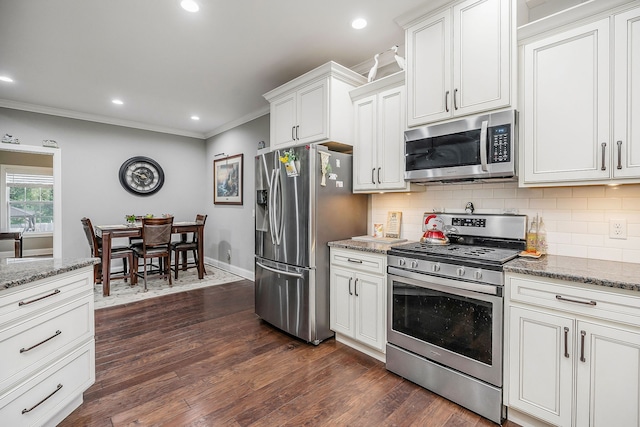 kitchen featuring dark hardwood / wood-style flooring, stainless steel appliances, ornamental molding, white cabinetry, and dark stone countertops