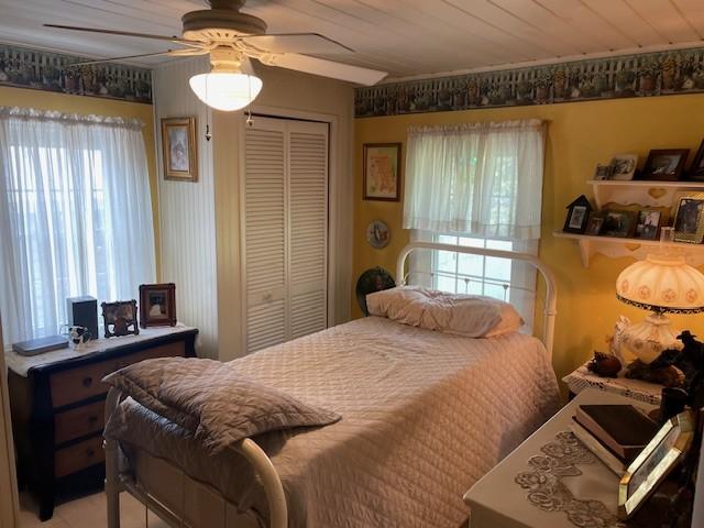 bedroom with a closet, wood ceiling, and a ceiling fan