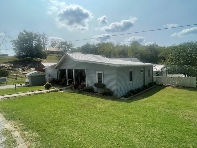rear view of house featuring fence and a lawn
