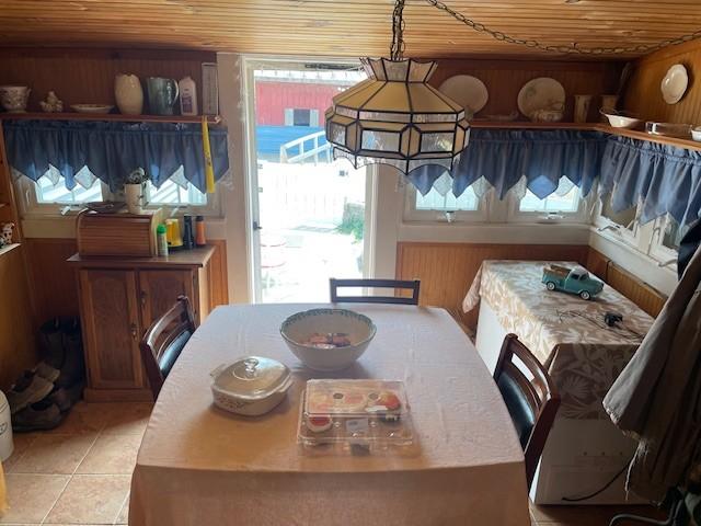 dining area with wood ceiling, wood walls, and light tile patterned flooring