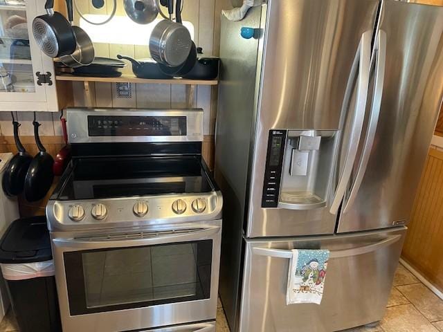 kitchen with decorative backsplash, light tile patterned floors, and stainless steel appliances