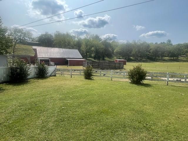 view of yard featuring an outdoor structure, an outbuilding, fence, and a rural view