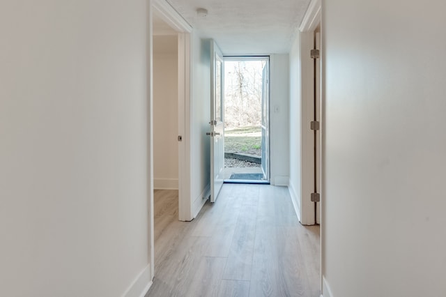 hallway with a textured ceiling and light hardwood / wood-style floors