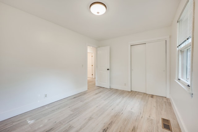 unfurnished bedroom with a closet and light hardwood / wood-style floors