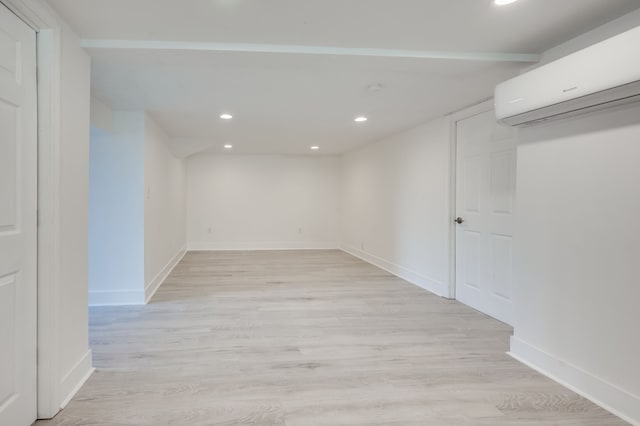 basement featuring a wall unit AC and light hardwood / wood-style flooring