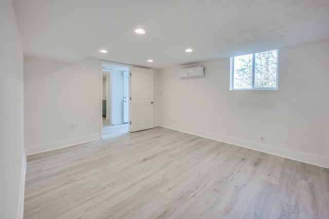 empty room featuring a wall unit AC and light wood-type flooring