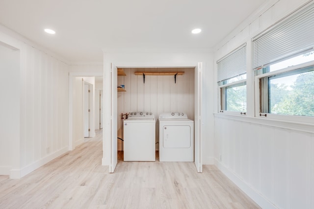 washroom with crown molding, washer and clothes dryer, and light hardwood / wood-style floors