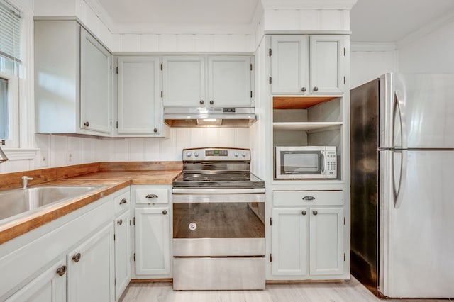 kitchen with light wood-type flooring, ornamental molding, and appliances with stainless steel finishes