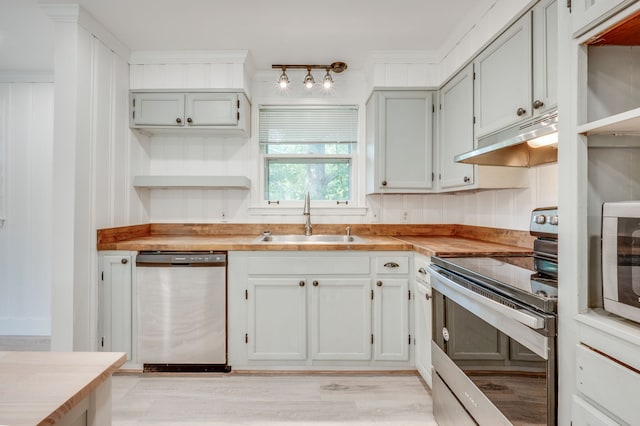 kitchen featuring stainless steel appliances, light hardwood / wood-style floors, sink, wooden counters, and ornamental molding