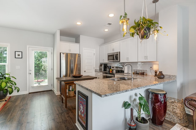 kitchen featuring backsplash, sink, decorative light fixtures, white cabinetry, and stainless steel appliances