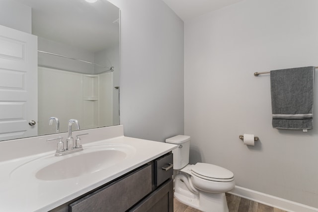 bathroom with hardwood / wood-style floors, vanity, toilet, and walk in shower