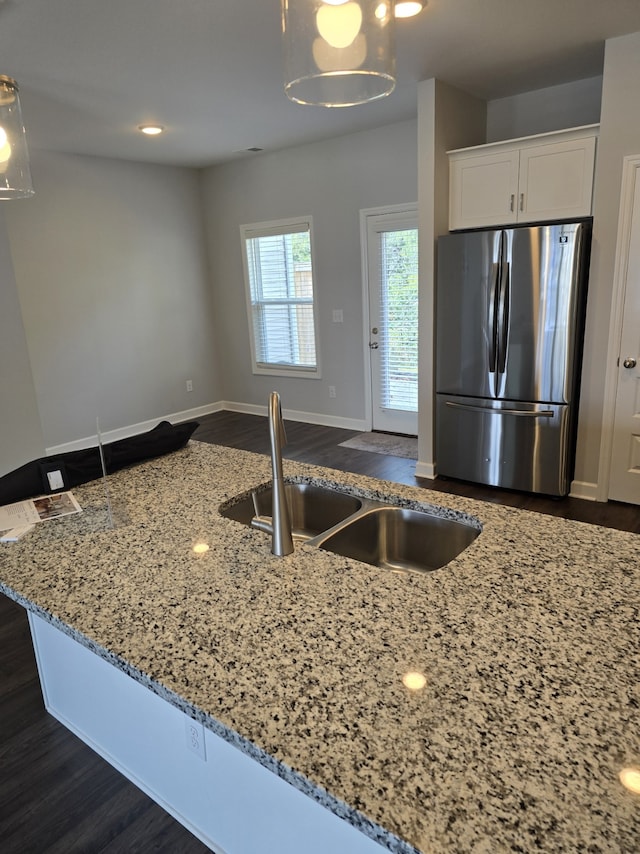 kitchen featuring stainless steel fridge, dark hardwood / wood-style flooring, light stone counters, sink, and white cabinets