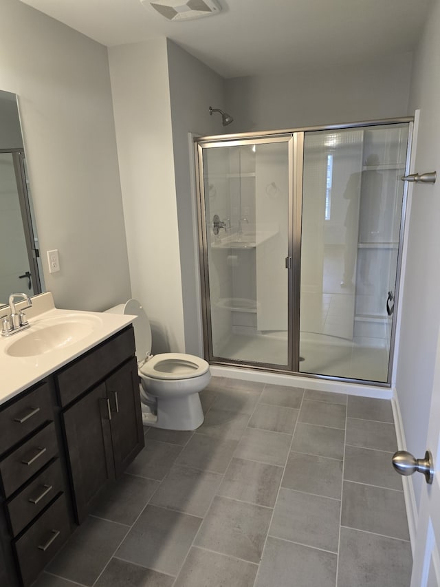 bathroom featuring tile patterned floors, vanity, an enclosed shower, and toilet