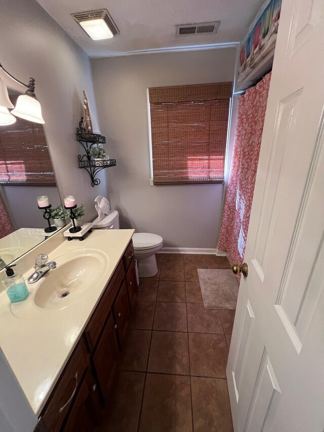 bathroom with a textured ceiling, vanity, curtained shower, toilet, and tile patterned floors