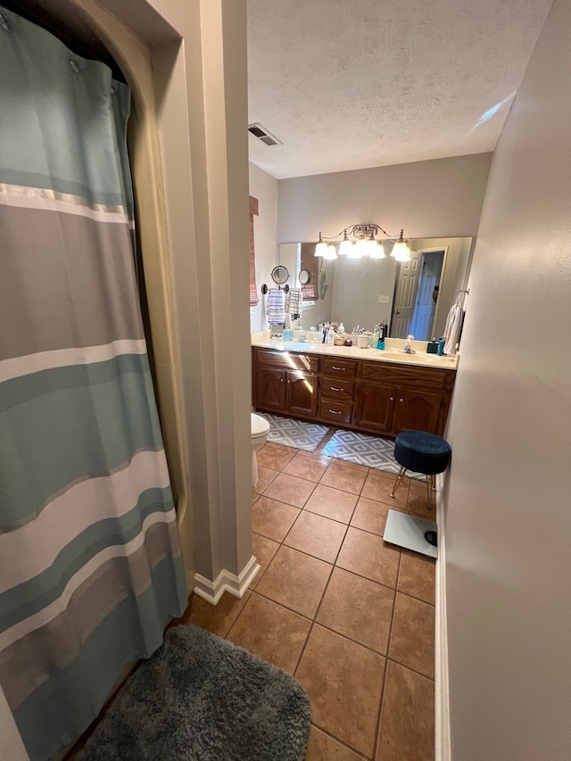 bathroom featuring a shower with shower curtain, tile patterned flooring, toilet, vanity, and a textured ceiling