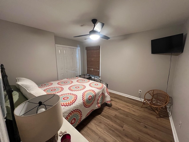 bedroom with ceiling fan, wood finished floors, a closet, and baseboards
