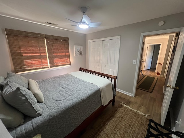 bedroom with visible vents, a ceiling fan, wood finished floors, a closet, and baseboards