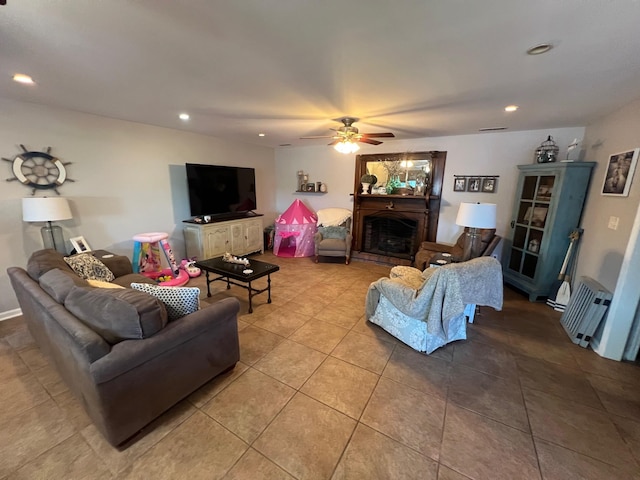 living area featuring tile patterned floors, recessed lighting, a fireplace with raised hearth, and a ceiling fan