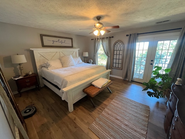 bedroom with a textured ceiling, access to outside, dark hardwood / wood-style flooring, ceiling fan, and french doors