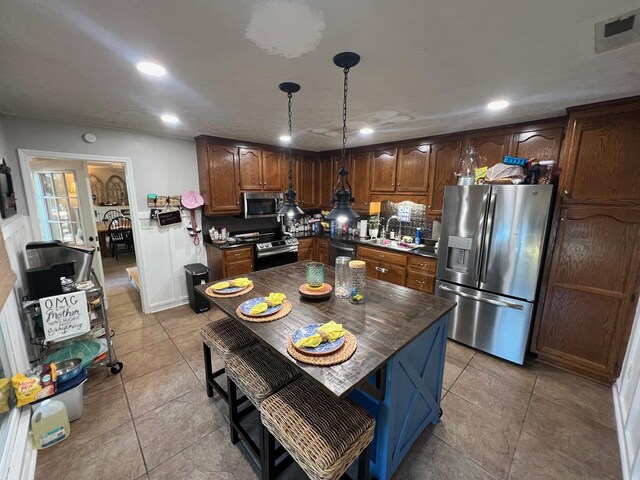 kitchen with backsplash, hanging light fixtures, stainless steel appliances, sink, and light tile patterned flooring