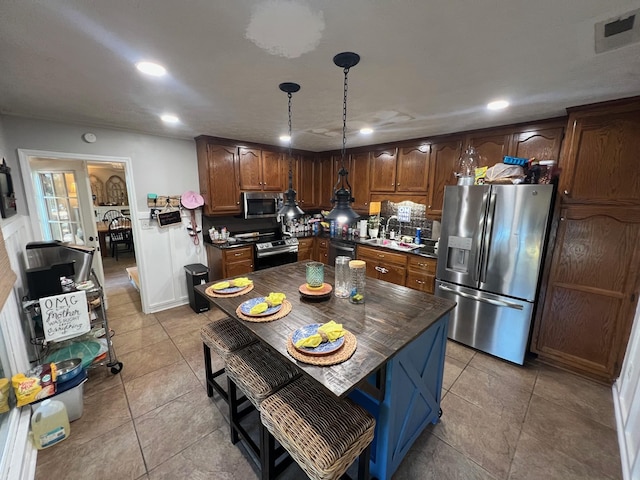 kitchen featuring visible vents, a sink, dark countertops, stainless steel appliances, and light tile patterned floors