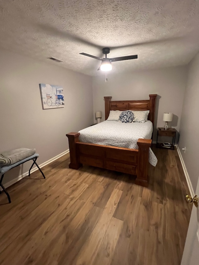 bedroom with a textured ceiling, ceiling fan, and dark hardwood / wood-style floors