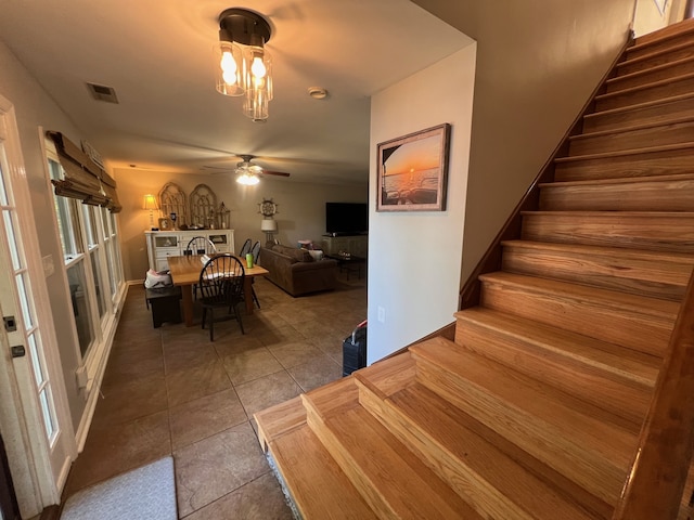 stairs featuring ceiling fan and tile patterned floors