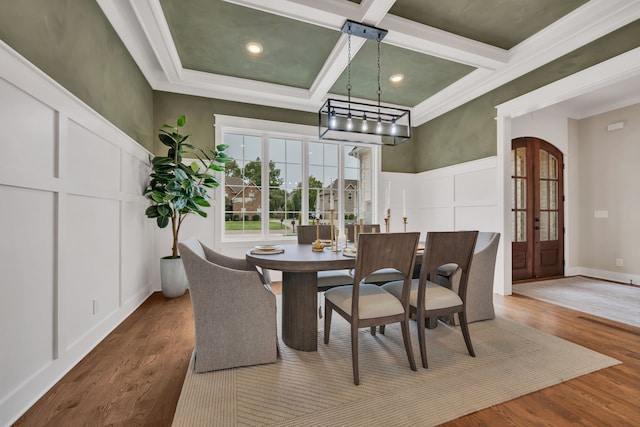 dining room featuring hardwood / wood-style flooring, a notable chandelier, coffered ceiling, beam ceiling, and ornamental molding