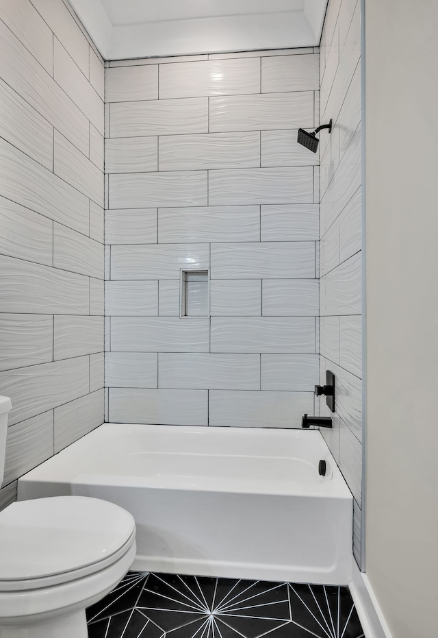 bathroom with tiled shower / bath, toilet, and tile patterned floors