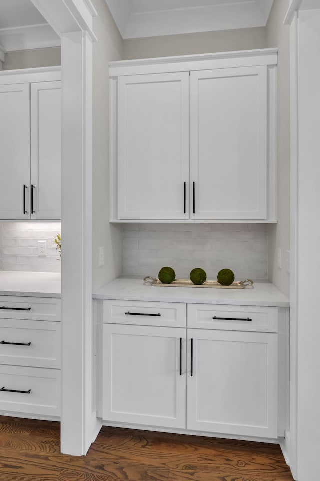 bar with dark wood-type flooring, white cabinetry, and backsplash