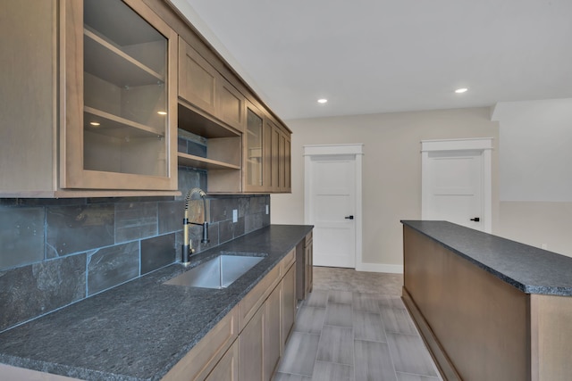 kitchen with dark stone counters, tasteful backsplash, and sink