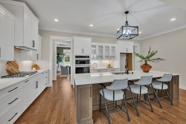 kitchen with dark wood-type flooring, white cabinetry, an island with sink, and sink