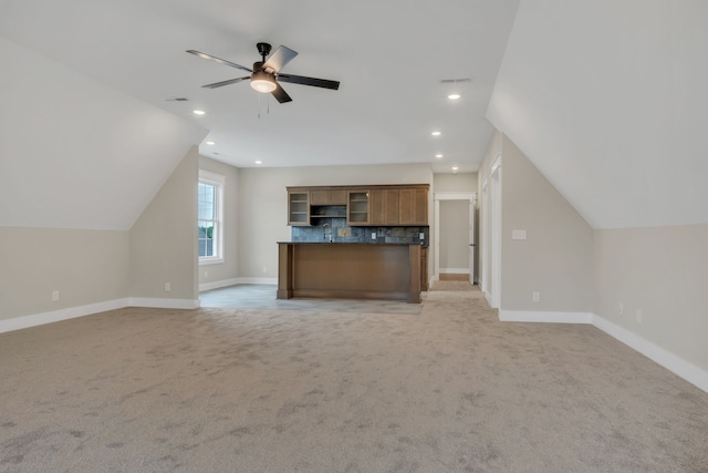 unfurnished living room with ceiling fan, light colored carpet, and vaulted ceiling